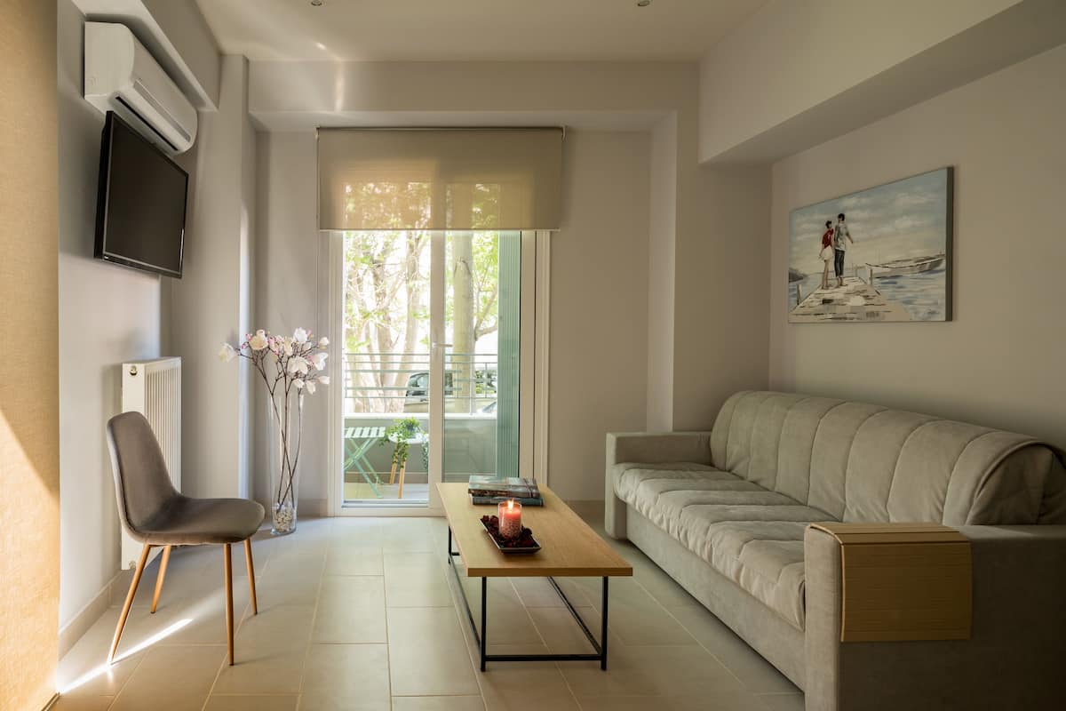 Un salon moderne avec un canapé, une table basse, un fauteuil et un téléviseur fixé au mur.