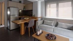 A modern kitchen with a built-in refrigerator, wooden dining table, and grey sofa. - 12 Keys Athens Apartments (Athens)