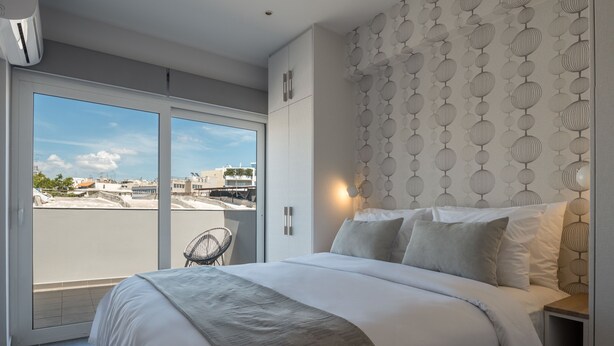 A modern bedroom with a large bed, a view through a sliding door to the outside, and a patterned wall. - 12 Keys Athens Apartments (Athens)