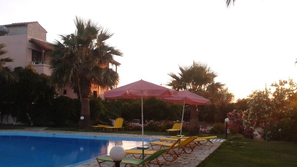 A swimming pool area with lounge chairs and umbrellas. - Pardalakis Studios (Platanias)