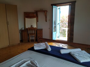 A bedroom with a bed, a wooden dresser, a chair, a desk, and a window with a view of a balcony. - Pardalakis Studios (Platanias)