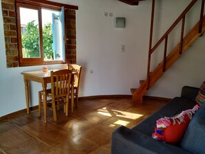 Una habitación con una mesa y sillas de madera, una escalera y un sofá.