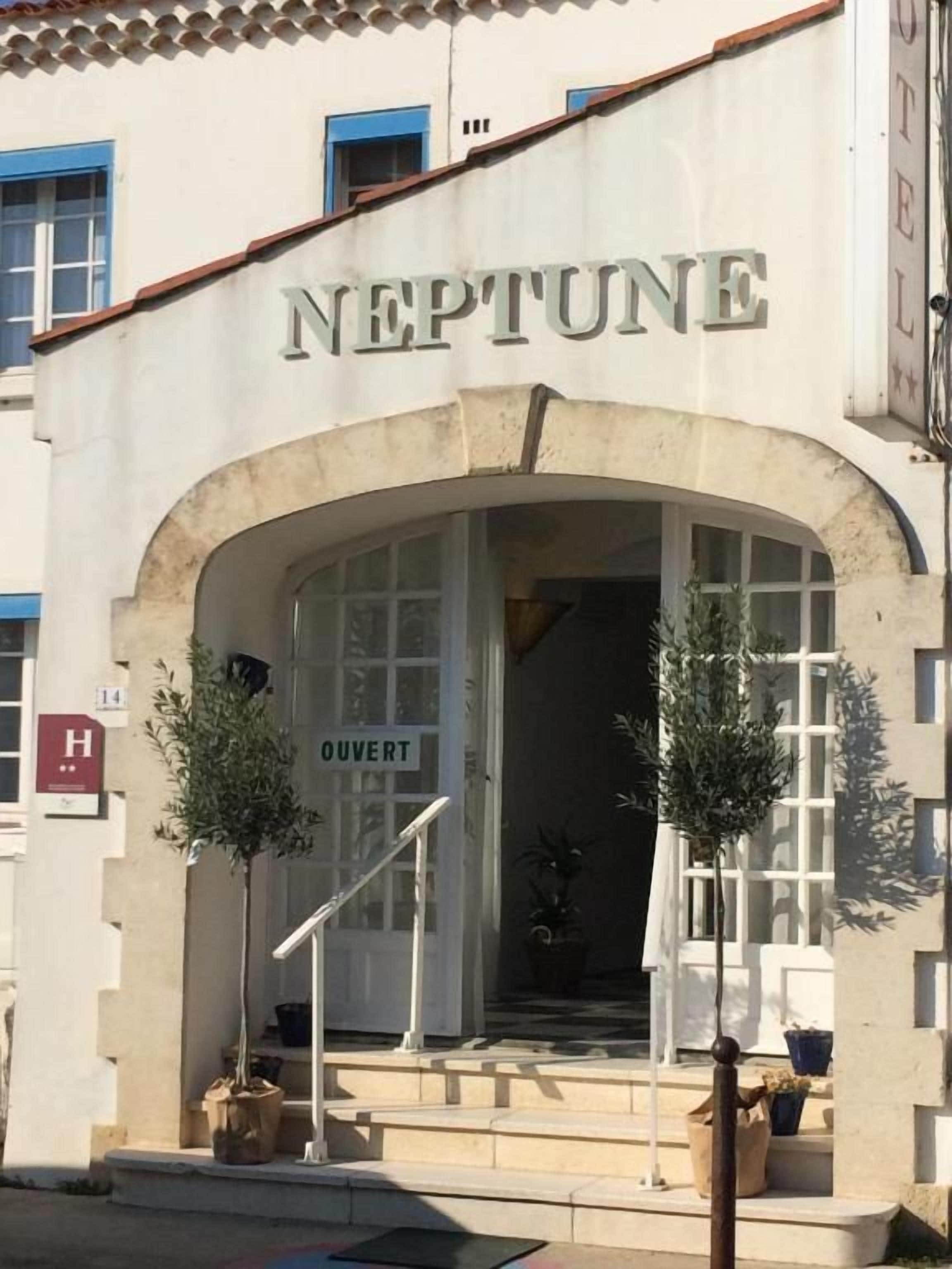 Un hôtel appelé « NEPTUNE », doté d’une entrée en arc de cercle, d’une enseigne indiquant « OUVERT » et d’un escalier menant à l’entrée.