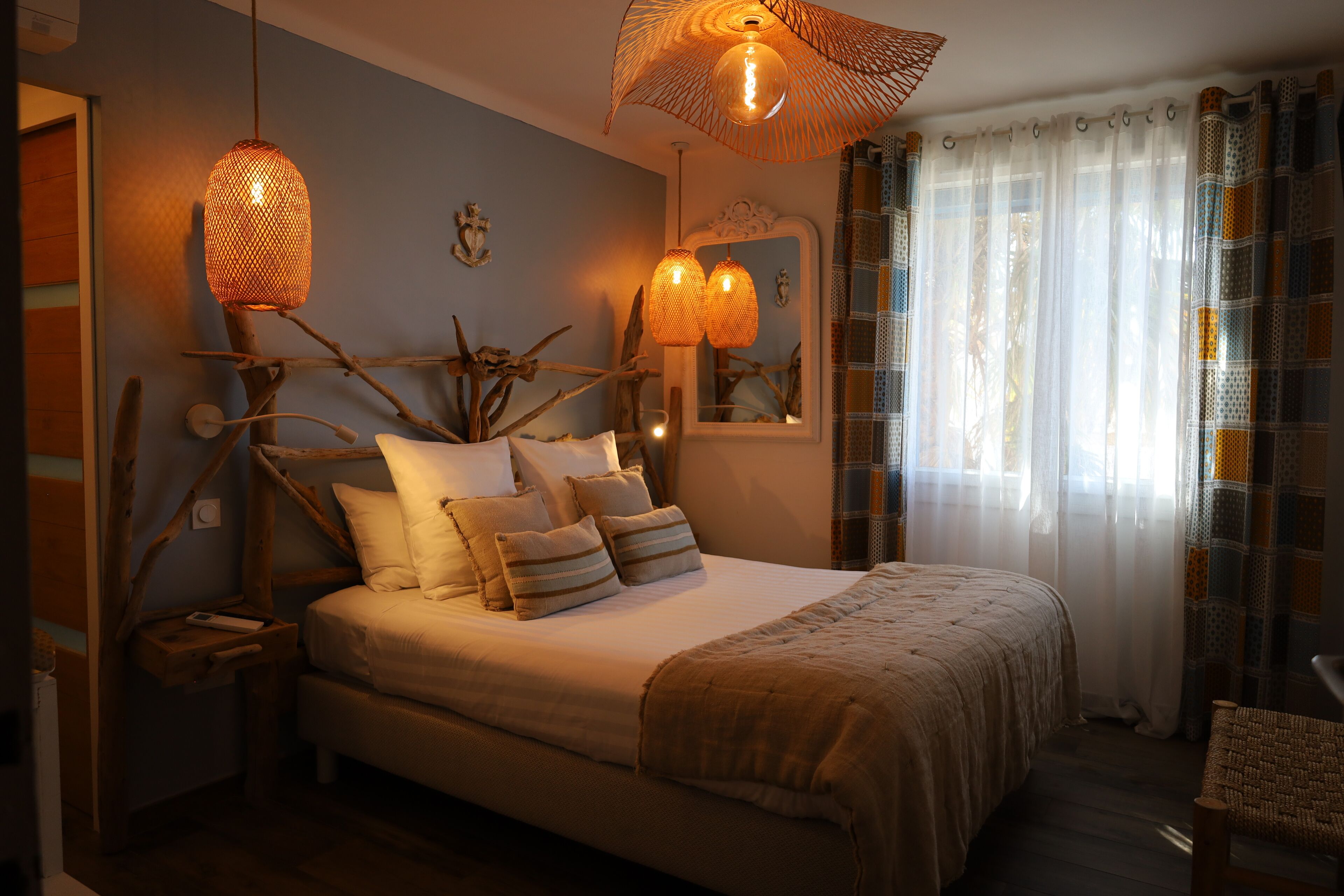 Une chambre à coucher avec un grand lit, deux lampes de chevet, un miroir et une fenêtre avec des rideaux.