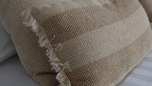 Un lit avec une literie blanche et des oreillers beiges à texture.
