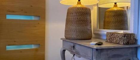 A wooden sliding door with a modern design, a small table with a lamp, and a mirror on the wall.