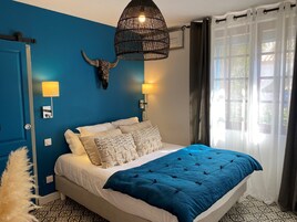 Un dormitorio con pared azul, una cama con colcha azul y blanca, un cráneo decorativo en la pared y una lámpara colgante.
