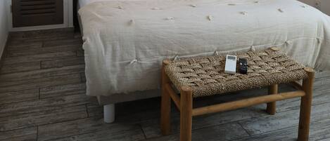 A bedroom with a bed, bedside lamps, a wall-mounted picture, and a wooden bench.