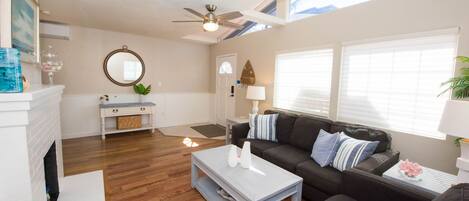 A living room with a fireplace, a sofa, a coffee table, and a ceiling fan.