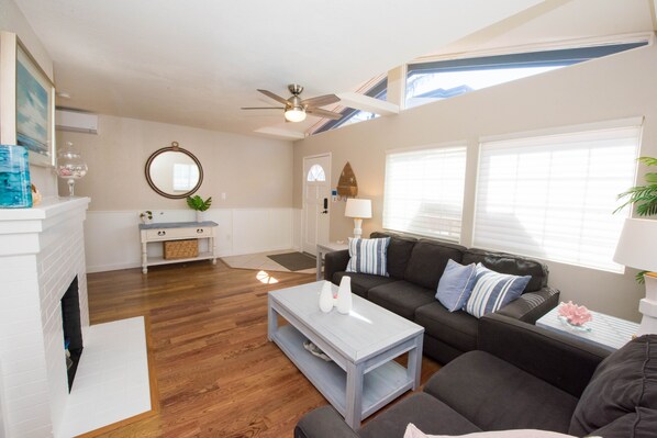 A living room with a fireplace, a sofa, a coffee table, and a ceiling fan.