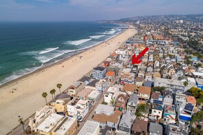 An aerial view of a coastal town with a beach, houses, and a pier.