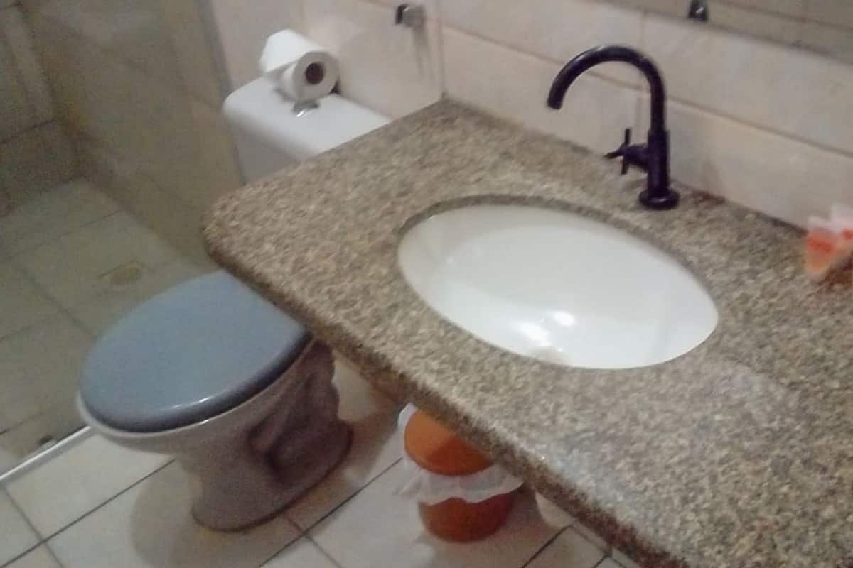 A bathroom with a toilet, sink, and faucet.
