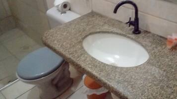 A bathroom with a toilet, sink, and faucet.