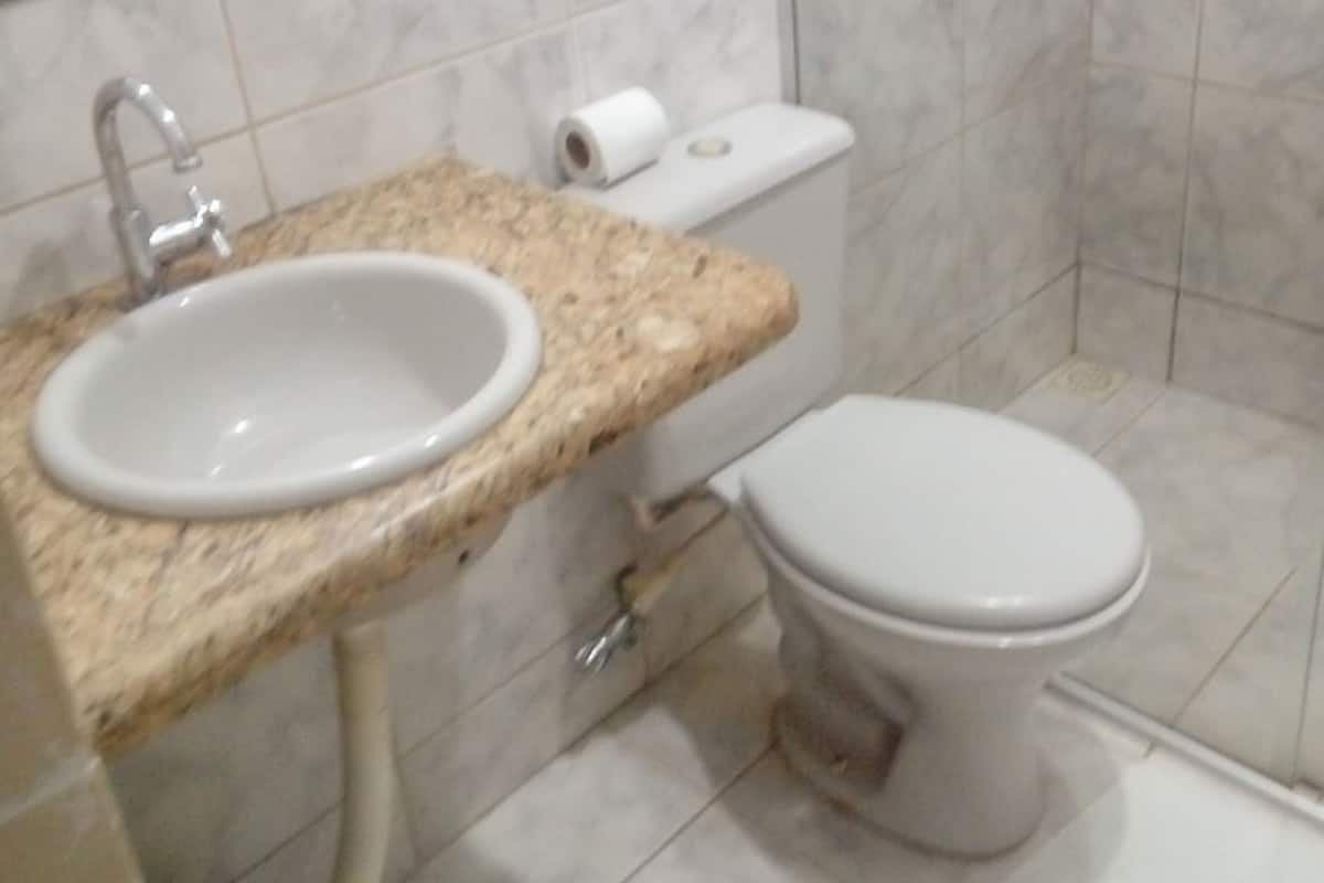 A bathroom with a white sink, toilet, and marble countertop.