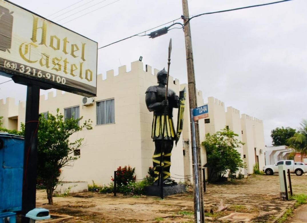 Uma estátua de um cavaleiro em armadura, um letreiro do Hotel Castillo e uma placa de rua azul.