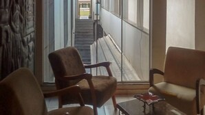 A room with two armchairs and a small table, a view of a staircase leading outside, and a wall with a textured pattern. - Hotel Castelo (Palmas)