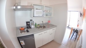 A compact kitchen with a microwave, sink, and coffee maker. There is a small refrigerator and a dishwasher. The kitchen has white cabinets and a white countertop. - Loft Cielo Abierto (Valparaiso)