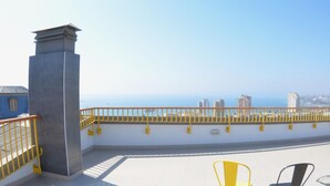 A rooftop terrace with a yellow railing, two chairs, and a view of the cityscape and ocean. - Loft Cielo Abierto (Valparaiso)