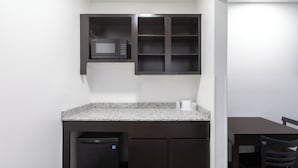 A compact kitchen with a microwave, a dishwasher, and a dining area with a table and chairs. - Motel 6 Greenville, SC - I-85 Near Downtown (Greenville)