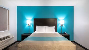 Habitación de hotel con cama, dos mesitas de noche, lámpara y ventana con cortinas.