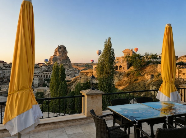 A terrace with yellow umbrellas, a table, and chairs.