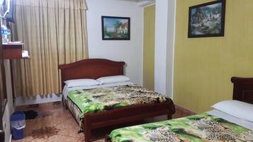 Un dormitorio con una cama de madera, una mesita de noche pequeña y dos cuadros enmarcados en la pared.