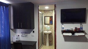 Un baño con lavabo, espejo y repisa con artículos de aseo.