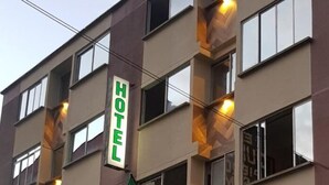 Un edificio de hotel con varios pisos, un letrero que indica que es un hotel y banderas colgando del edificio.