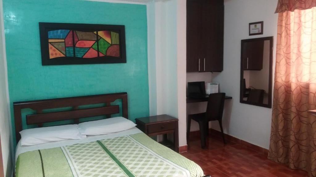 A bedroom with a bed, a desk, a chair, and a wardrobe.