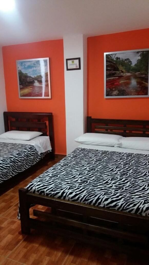 A room with two beds, each with a zebra print bedspread, wooden headboards, and white pillows.