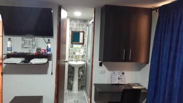 A compact bathroom with a white sink, a mirror, a towel rack, and a dark wooden cabinet.