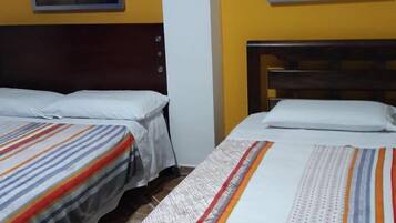 Una habitación de hotel con dos camas individuales, un cabecero de madera y dos cuadros en las paredes.