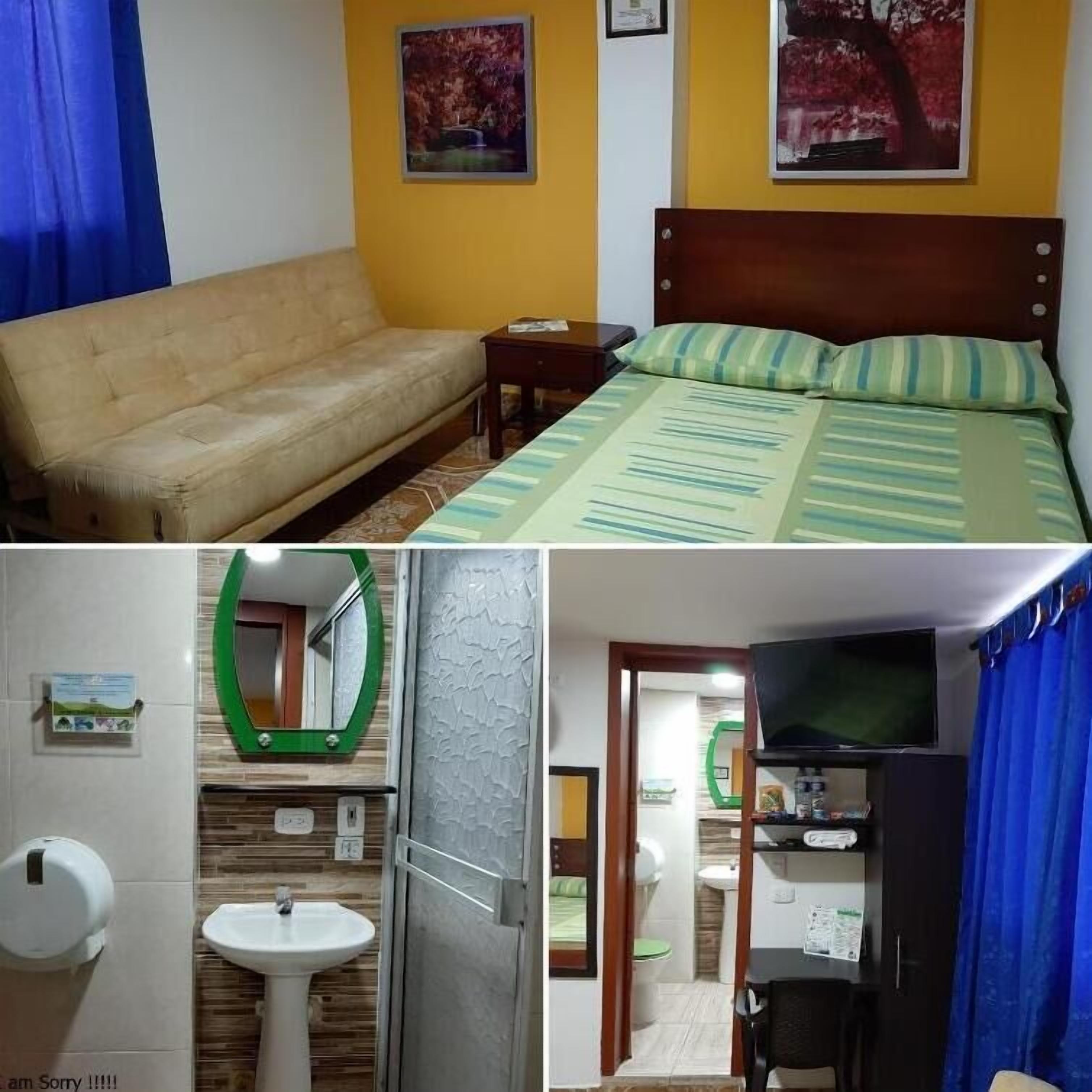 Un dormitorio con una cama, un sofá, una mesita de noche y dos cuadros en la pared.
