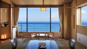 Habitación con un amplio ventanal que ofrece vista al mar, una mesa con sillas y una lámpara.