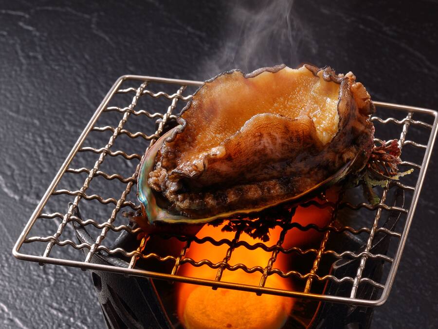 Ein gegrillter Auster auf einem Drahtrost über glühenden Kohlen.