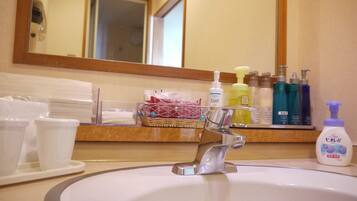 A hotel bathroom with a sink, toiletries, and a mirror.