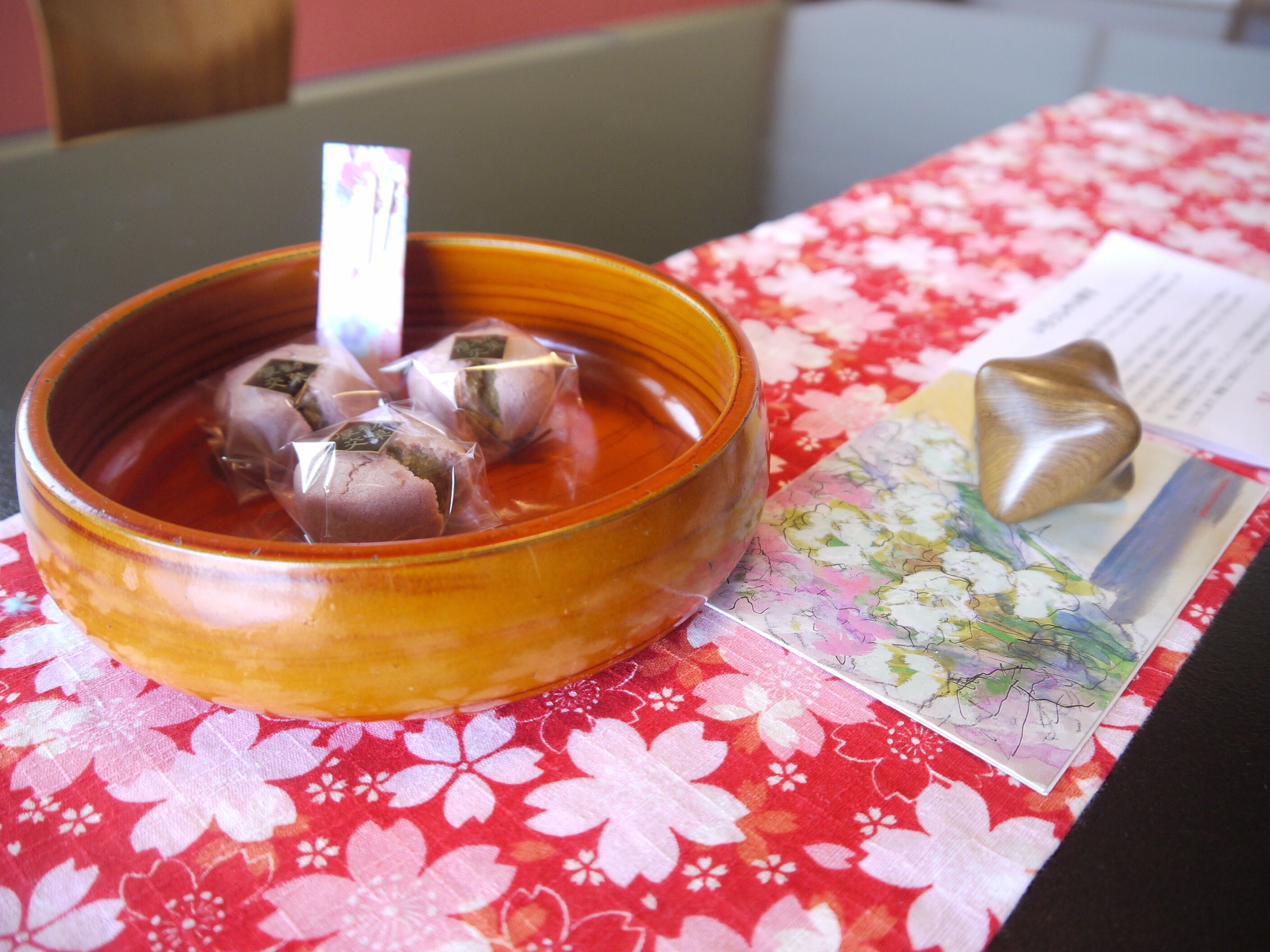 A bowl of food with a spoon, placed on a table with a floral tablecloth.