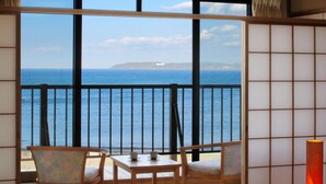 Una habitación con vistas al mar, un balcón con mesa y sillas, y un tradicional fusuma japonés.