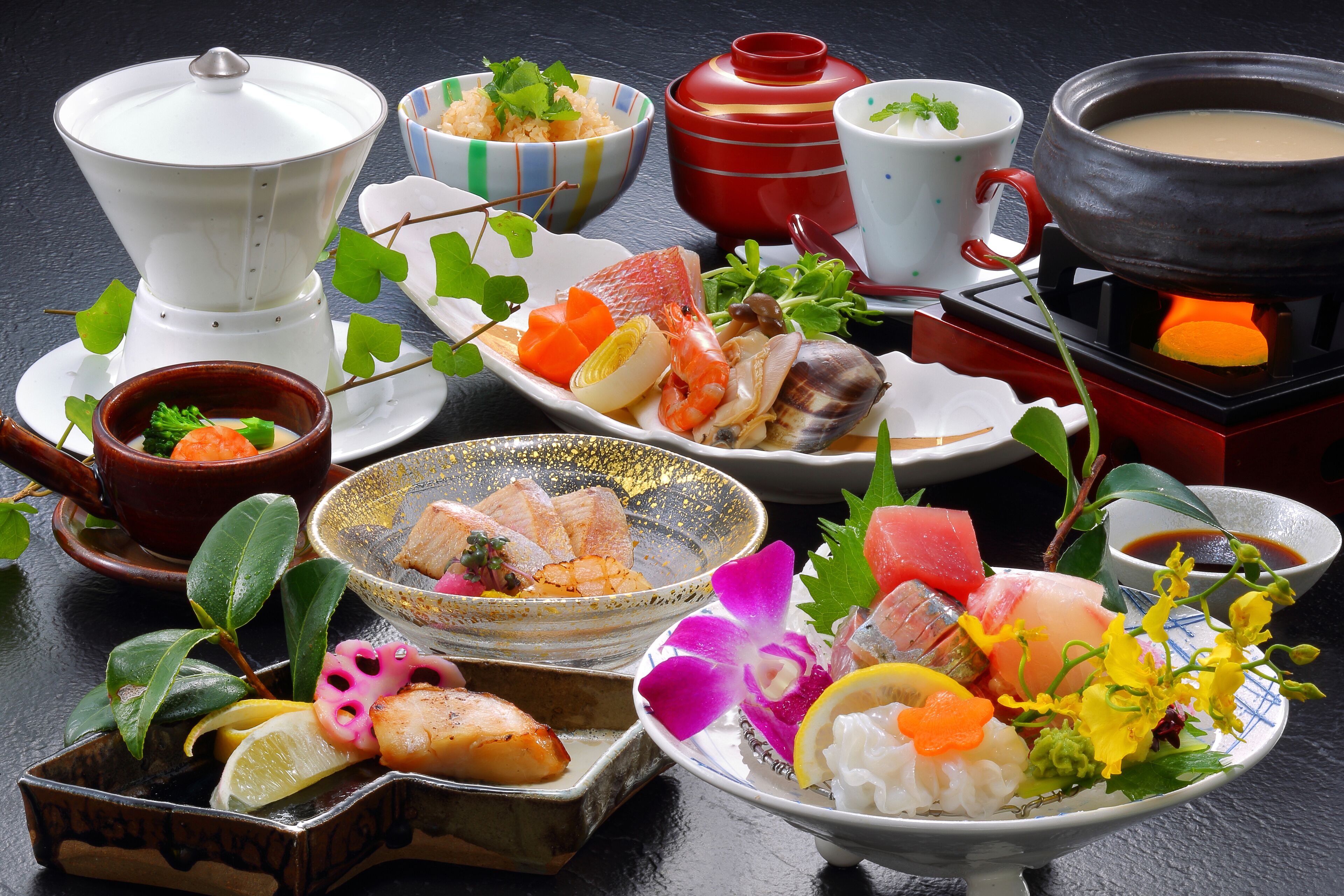 A variety of dishes and bowls on a table, including seafood, vegetables, and a hot pot.