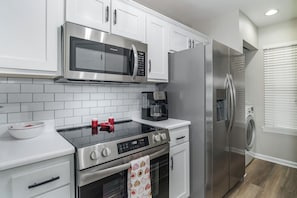 Una cocina moderna con armarios blancos, electrodomésticos de acero inoxidable y horno empotrado.