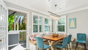 Een eethoek met een houten tafel, blauwe stoelen en een bank met gestreepte kussens.
