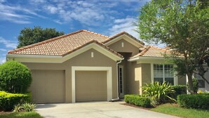 A two-story house with a tiled roof, a garage, and a well-maintained lawn. - Luxury Villa  2 miles from Disney  (Kissimmee)