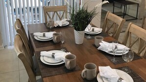 A dining area with a wooden table set for four, including plates, glasses, and a potted plant. - Luxury Villa  2 miles from Disney  (Kissimmee)