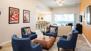 A living room with four blue armchairs, a coffee table, and two posters on the wall. - Luxury Villa  2 miles from Disney  (Kissimmee)
