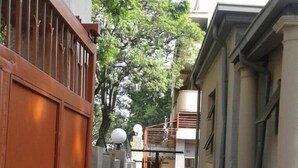 A narrow alleyway with a red gate, a paved path, and buildings on either side.
