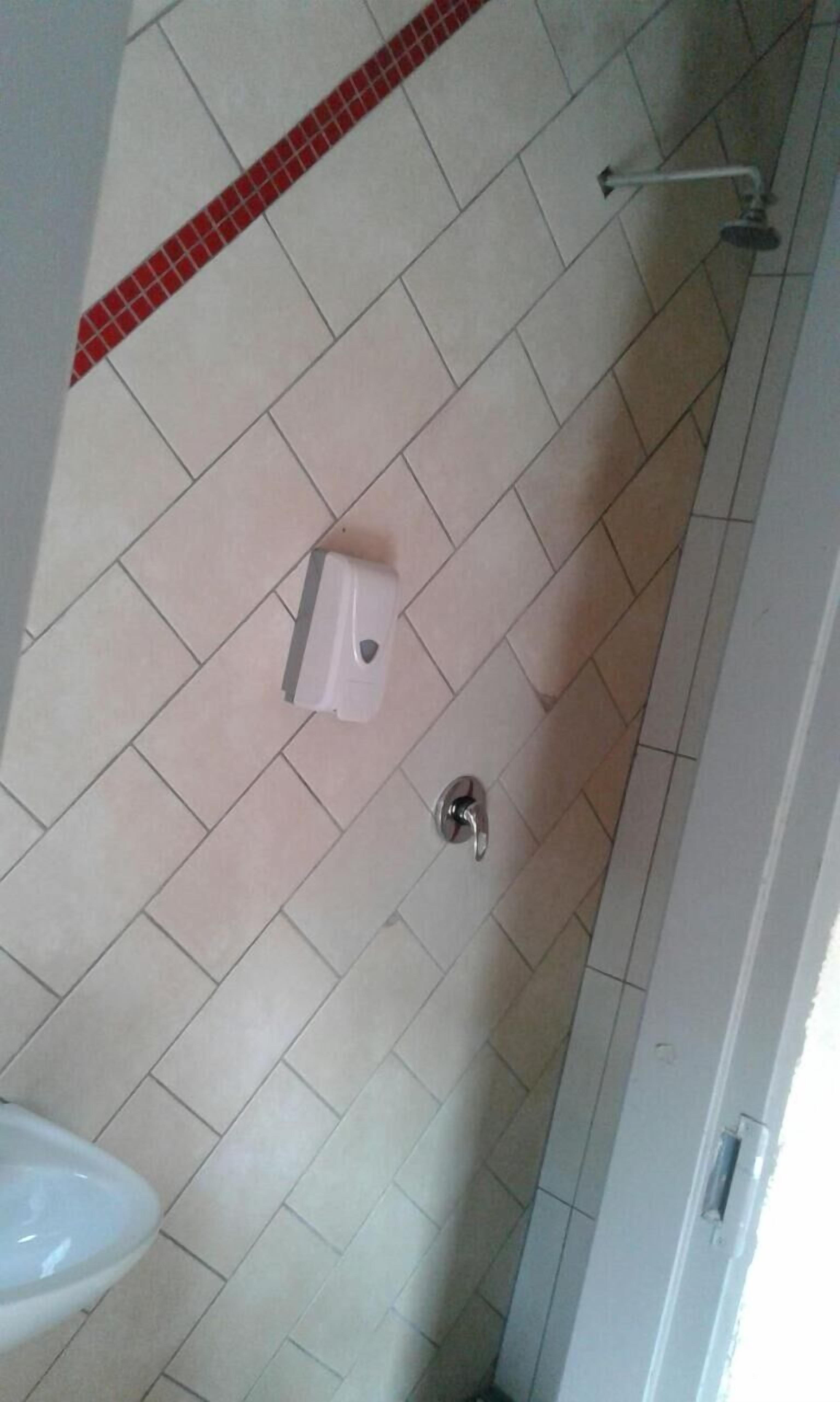 Un baño con inodoro, secamanos y zona de ducha.