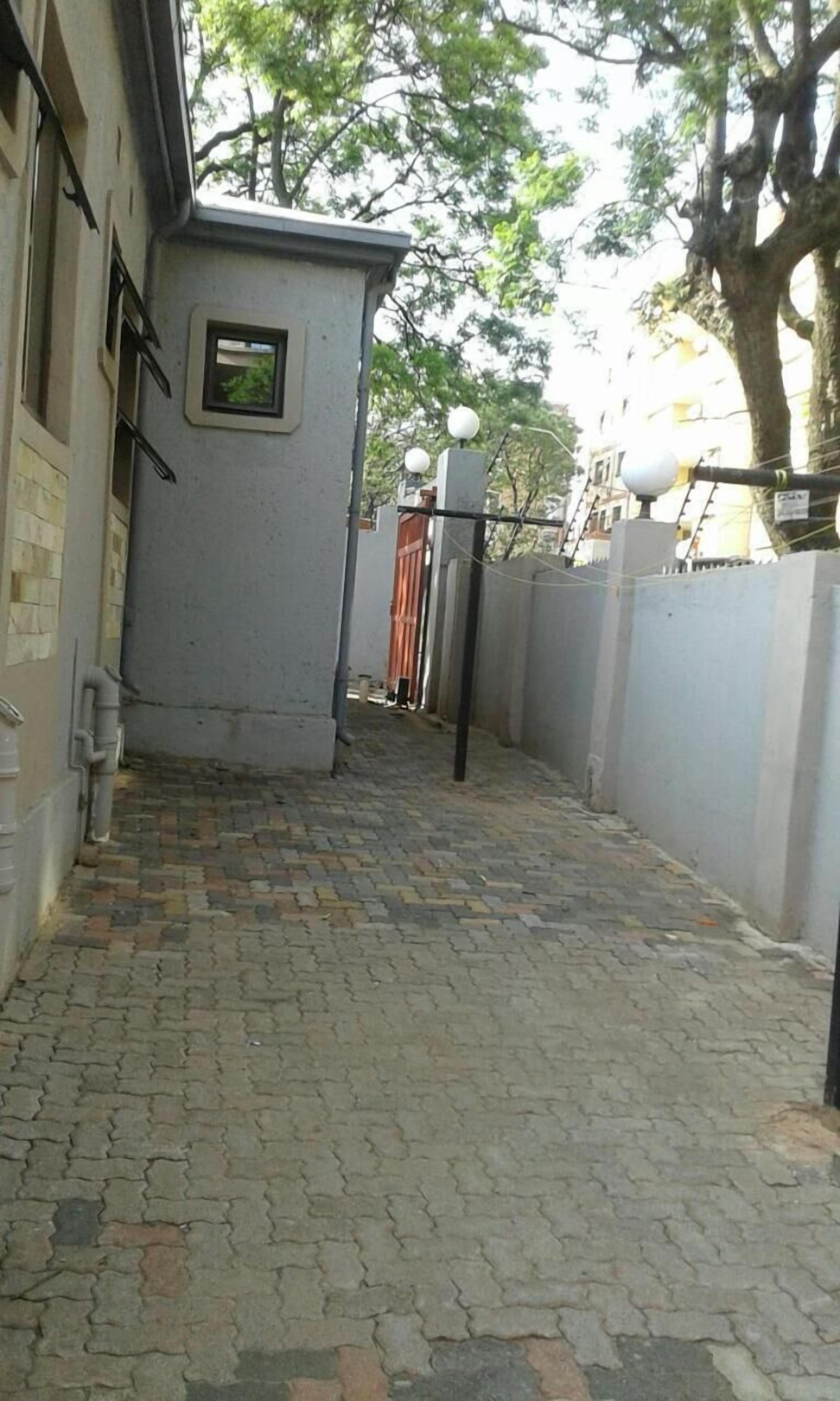 Un estrecho callejón con pavimento de adoquines, un pequeño edificio de servicios y una entrada con reja.