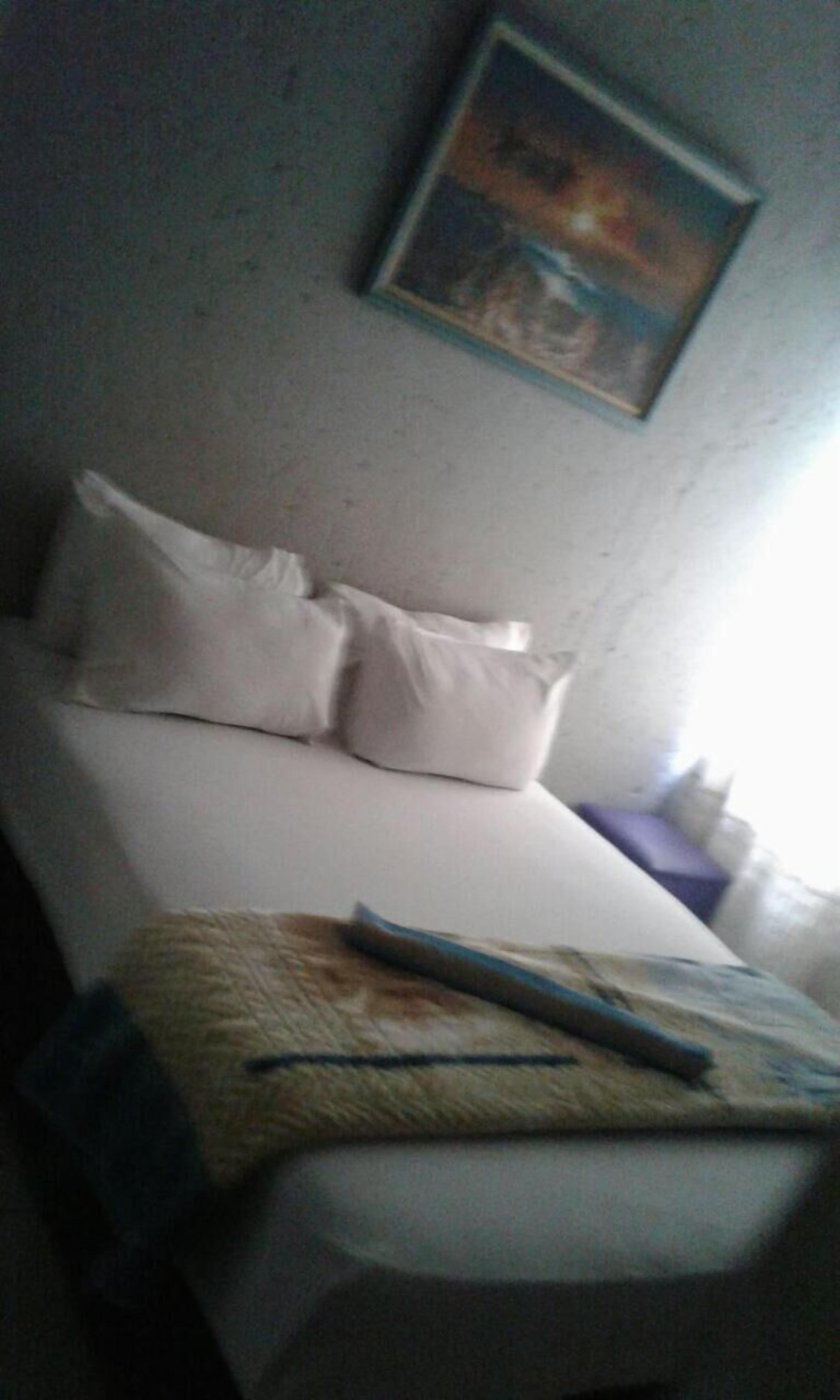 Une chambre d’hôtel avec un lit, des oreillers, une couverture et un tableau au mur.