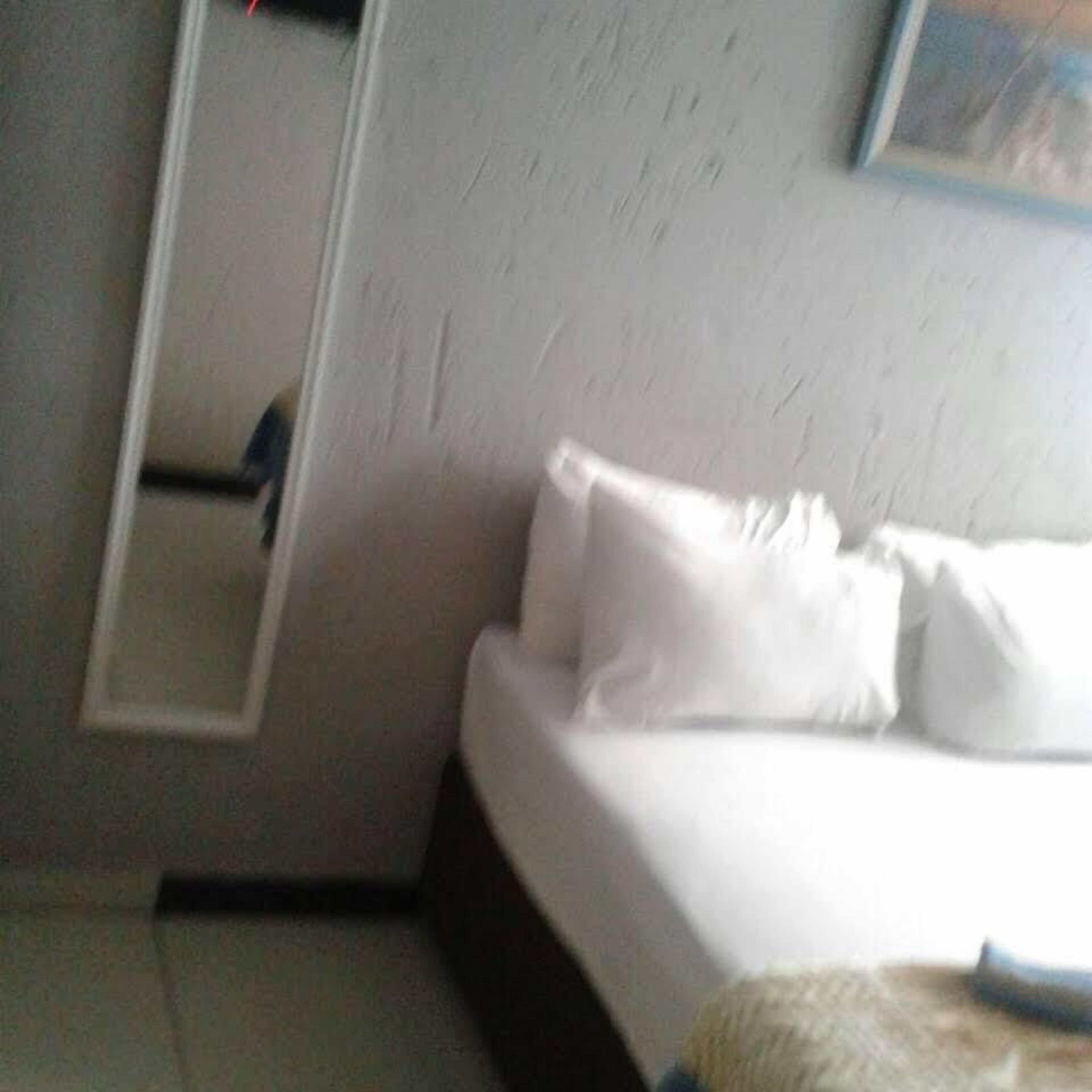 A hotel room with a bed, a nightstand, and a mirror on the wall.