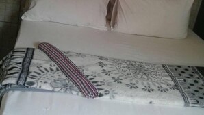 A bed with white bedding and a patterned blanket.
